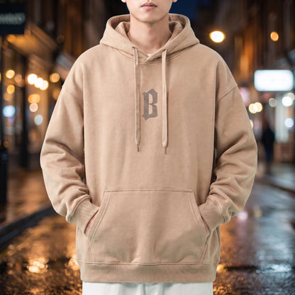 Vallor Gothic Hoodie in beige, oversized pullover with small blackletter B chest print, worn on a city street at night