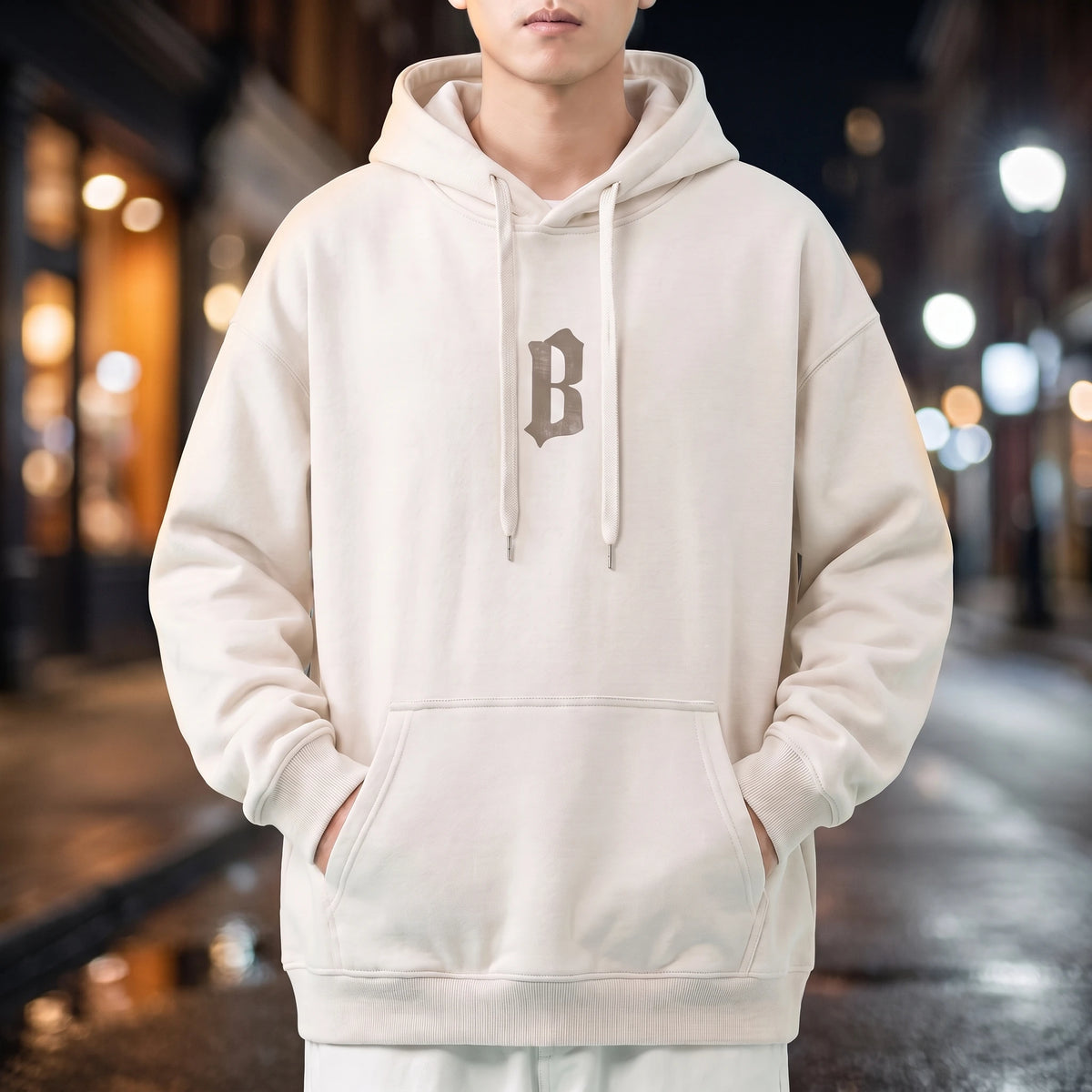 Vallor Gothic Hoodie in white, oversized pullover with small blackletter B chest print, worn on a city street at night
