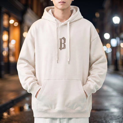 Vallor Gothic Hoodie in white, oversized pullover with small blackletter B chest print, worn on a city street at night