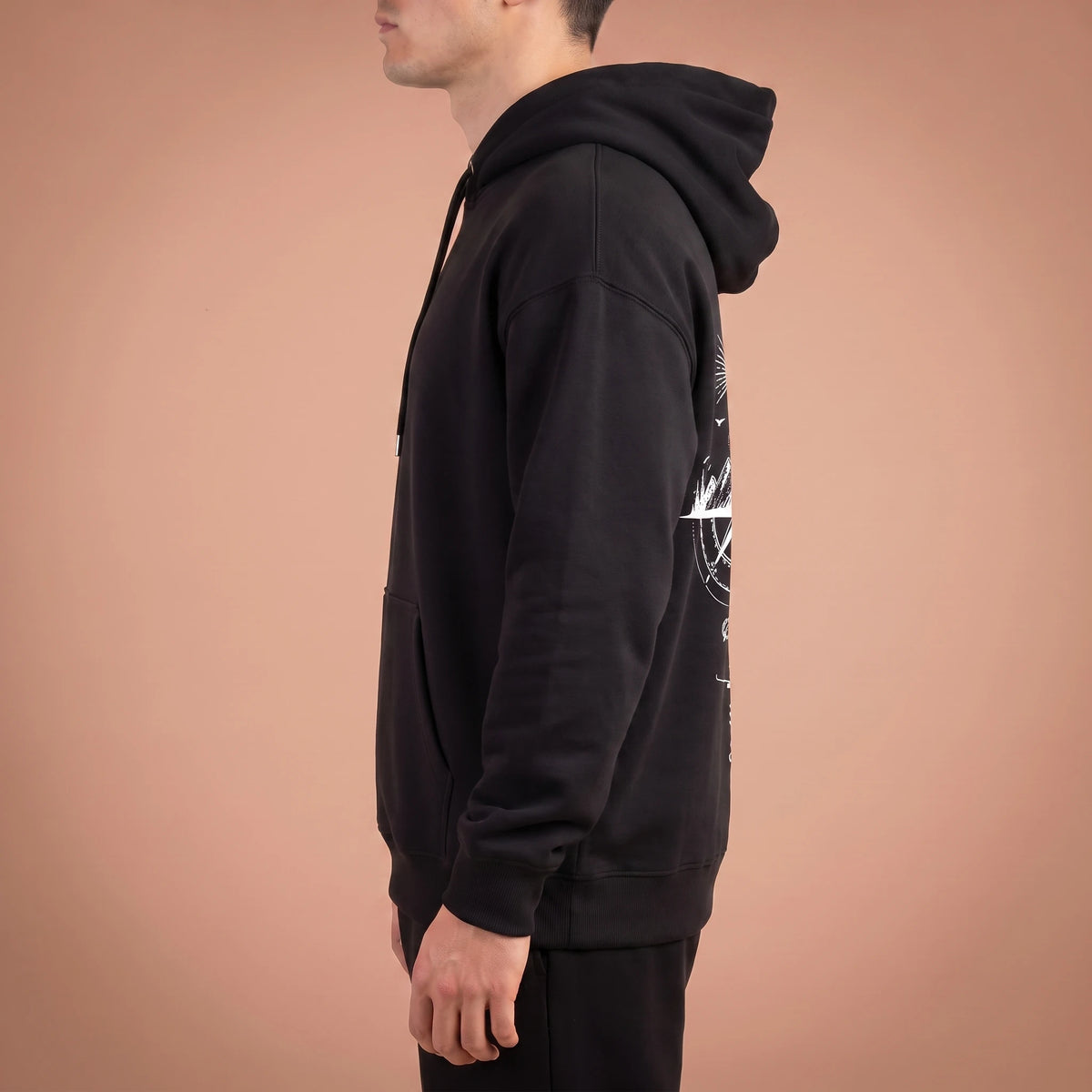 Solane Compass Hoodie in black, side profile showing plain sleeve, hood down and ribbed cuff