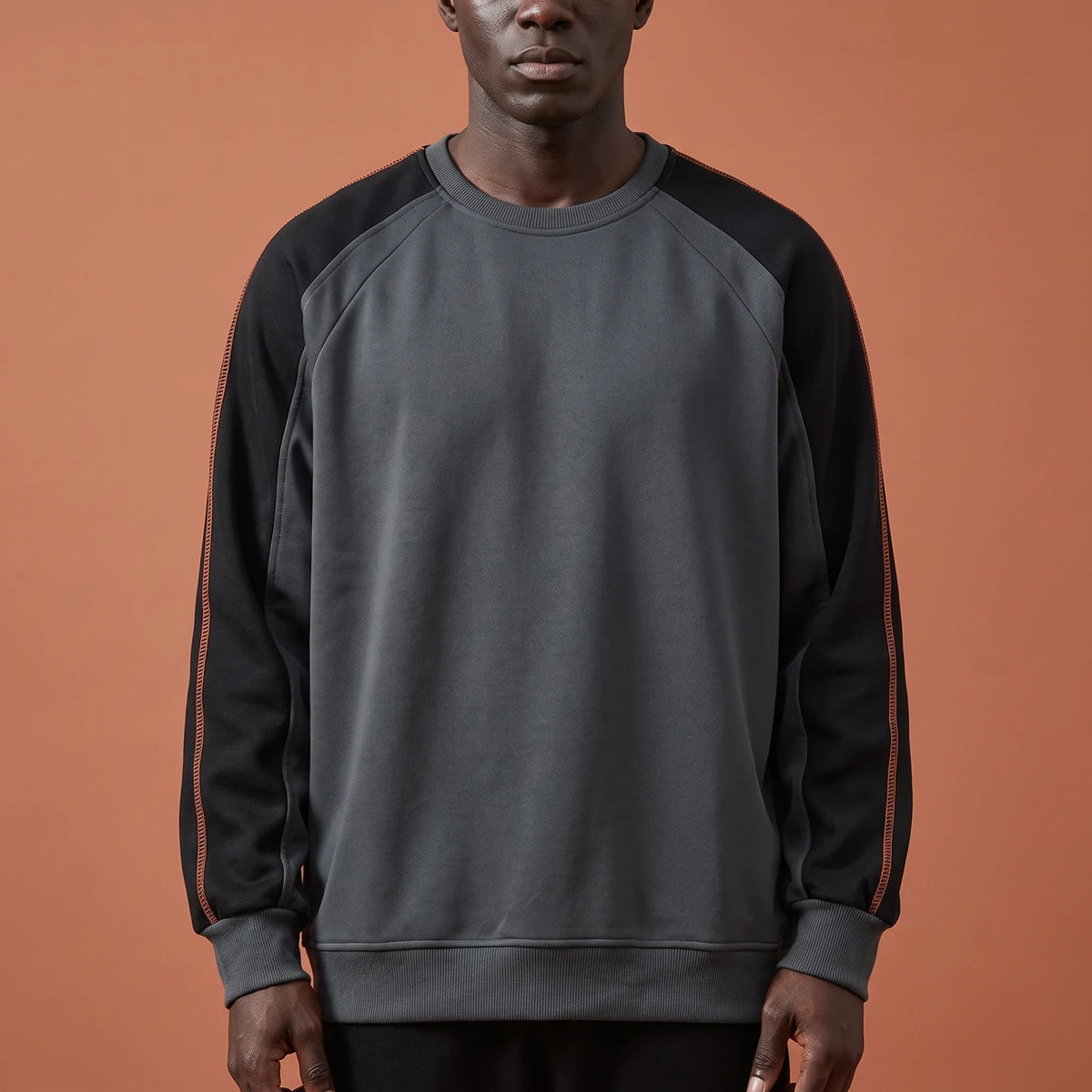 Tavish Stitch Crewneck in gray, men's raglan crewneck sweatshirt with black contrast sleeves and orange stitch line, studio shot