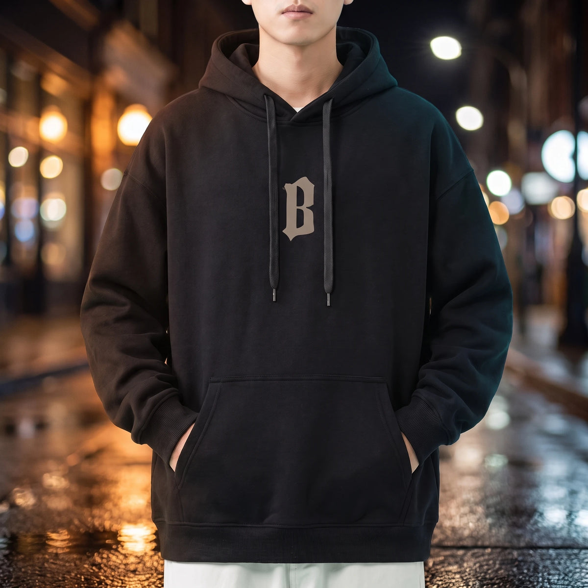 Vallor Gothic Hoodie in black, oversized pullover with small blackletter B chest print, worn on a city street at night